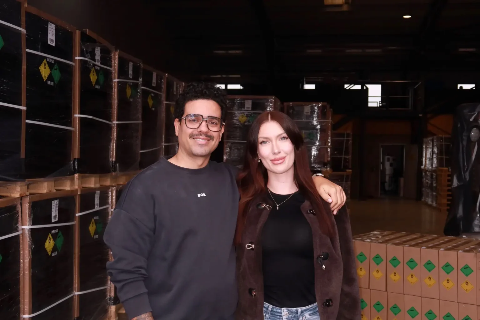 Danny e Nina Getu lado a lado em um armazém, entre paletes de produtos